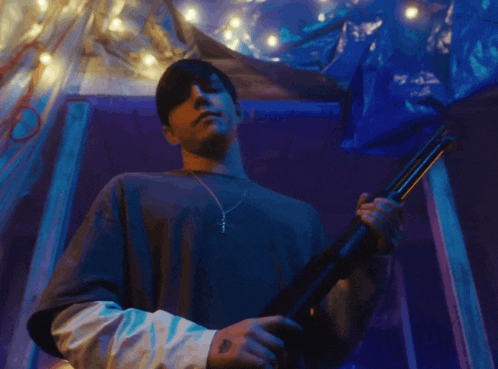 a man holding a shotgun with a cross necklace around his neck