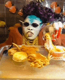 a person wearing a mask and sunglasses is sitting in front of a tray of food .