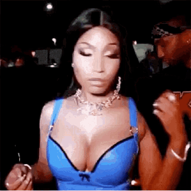a woman in a blue bra and necklace is standing in front of a man .