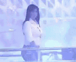 a woman in a white shirt is standing in front of a blue wall .