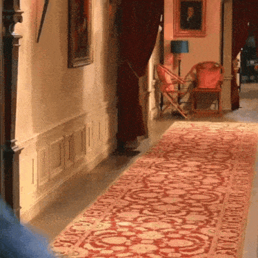a hallway with a red rug and a chair with a picture on the wall