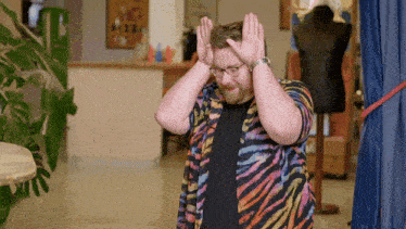 a man wearing a zebra print shirt is covering his head with his hands