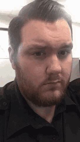 a man with a beard and a black shirt is making a funny face
