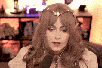 a woman is wearing a wig and a crown and talking into a microphone .