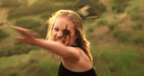a woman with blood on her face is standing in a field