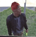 a man wearing a red hat and a black jacket is standing in a grassy area .