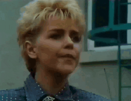 a woman with short blonde hair is wearing a blue shirt and a tie