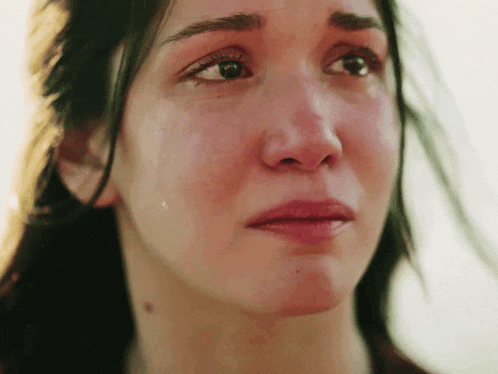 a close up of a woman 's face with a tear running down her cheek .