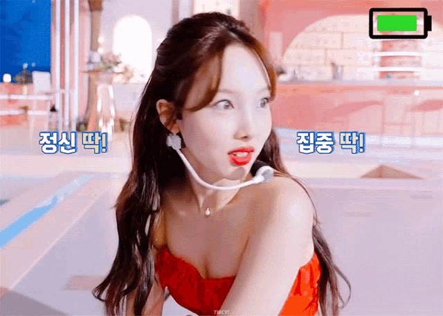 a woman wearing a red top and a microphone has korean writing on her face