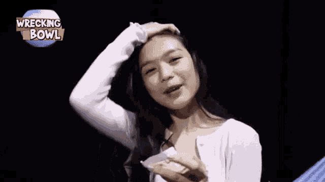 a woman in a white sweater is holding a piece of paper in front of her face .
