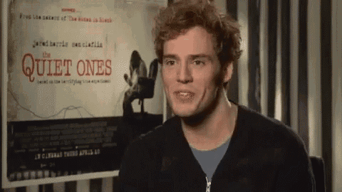 a man standing in front of a movie poster for the quiet ones
