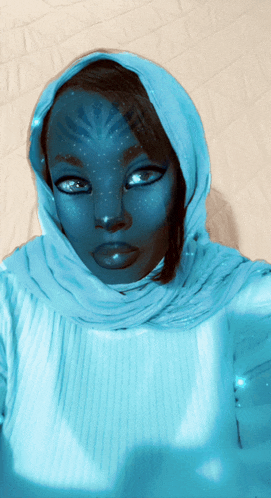 a woman wearing a blue head scarf has a blue face painted