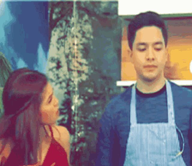 a man in an apron is standing next to a woman in a red dress