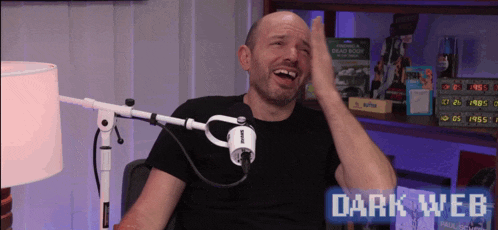 a man is laughing in front of a microphone with the words dark web on the bottom right