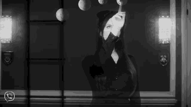 a black and white photo of a woman standing in front of a door .