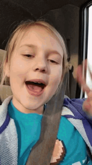 a little girl is wearing a seat belt and a blue shirt