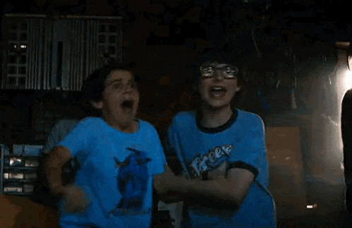 two boys are hugging each other in a dark room .