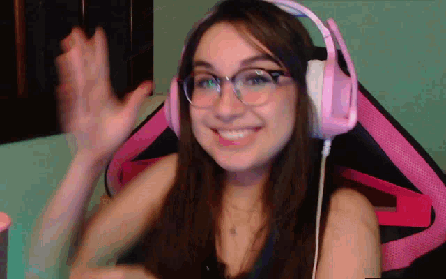 a woman wearing pink headphones and glasses is smiling