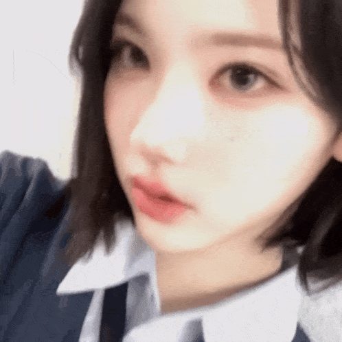 a close up of a girl 's face with short hair and a white shirt and tie .