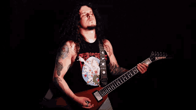 a man with long hair is playing a red guitar with a shirt that says dead force on it