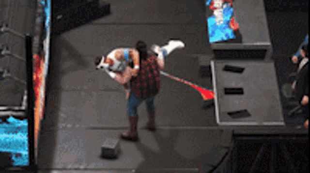 a wrestler is being lifted in the air by another wrestler while a crowd watches
