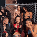 a group of women are sitting in front of a chain link fence and laughing .