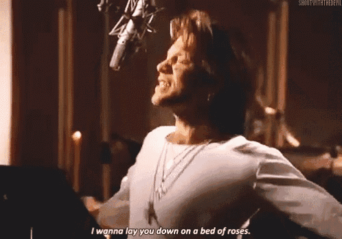 a man is singing into a microphone and saying i wanna lay you down on a bed of roses .