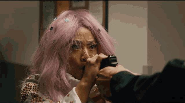 a woman with pink hair is holding a gun in her hand