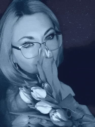 a woman wearing glasses holds a bouquet of white flowers