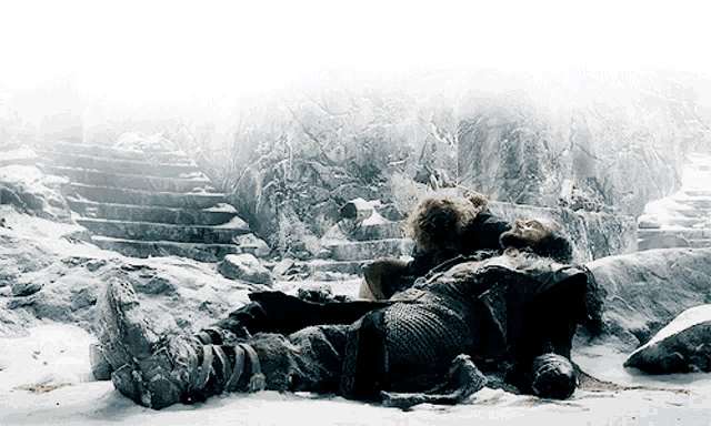 a man in armor is laying in the snow in front of some stairs