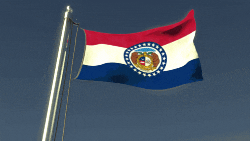a red white and blue flag is waving in the wind against a blue sky