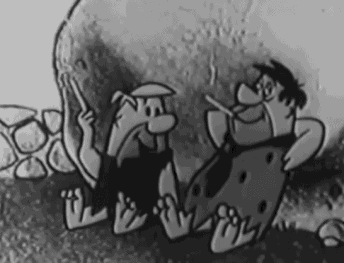 a black and white cartoon of the flintstones sitting next to a large rock .