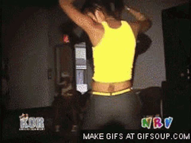 a woman in a yellow tank top is dancing in front of a sign that says nbv