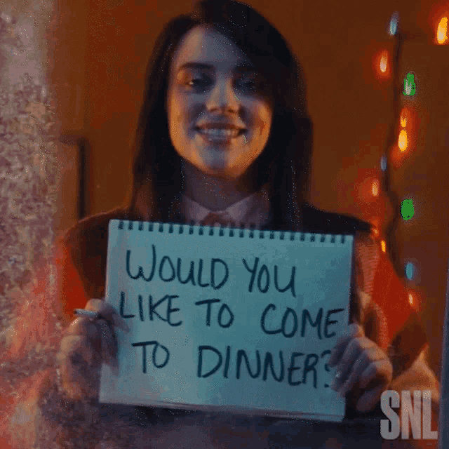 a woman holds up a sign that says would you like to come to dinner