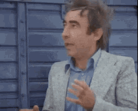 a man in a suit and blue shirt is making a funny face .