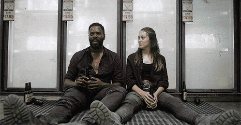 a man and a woman sit on the floor in front of a refrigerator with a sign that says 17.95 on it