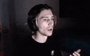 a man without a shirt is wearing headphones while dancing in a dark room .