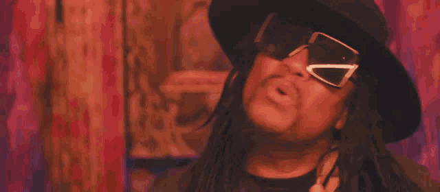 a man wearing a hat and sunglasses is making a face .