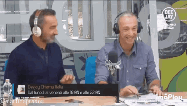 two men wearing headphones are sitting at a table in front of a deejay chiama italia sign