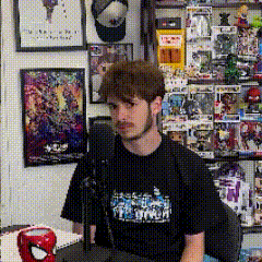 a man is sitting in front of a microphone wearing a t-shirt that says spiderman on it