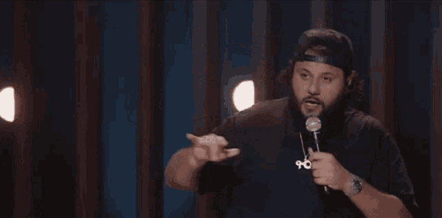 a man with a beard is holding a microphone on a stage and waving his hand .