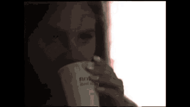 a woman is drinking a cup of coffee from a cup .