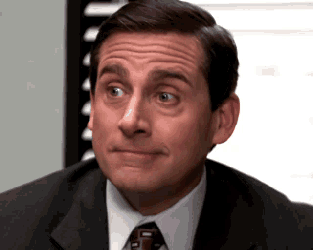 a man in a suit and tie is looking at the camera