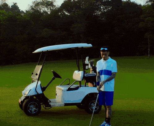 a man standing next to a golf cart with a golf club