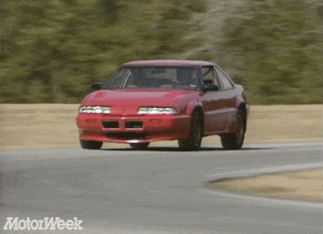 a red car is driving on a road with motorweek written on the bottom right