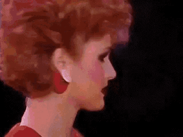 a woman with red hair and red earrings is wearing a red dress and red earrings .