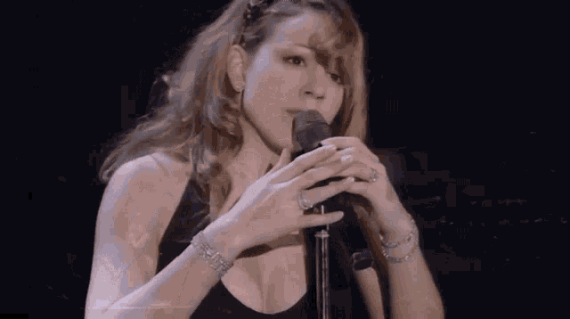 a woman is singing into a microphone while wearing a black top .