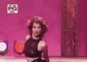 a woman in a black crop top is dancing on a stage .