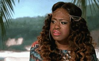 a woman with curly hair is wearing a headband and earrings and making a funny face .