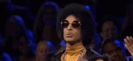 a man wearing sunglasses and a wig is making a peace sign .